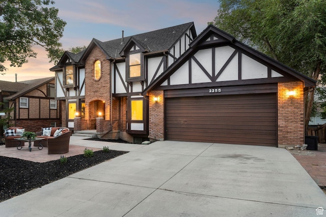 2255 E Camino Way Way S, Cottonwood Heights, UT 84121 - tudor home featuring brick siding, an outdoor living space, an attached garage, driveway, and stucco siding
