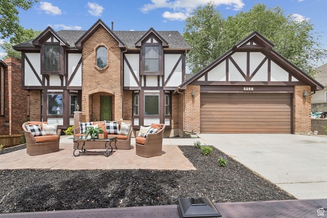 2255 E Camino Way Way S, Cottonwood Heights, UT 84121 - tudor-style house with an outdoor hangout area, an attached garage, concrete driveway, brick siding, and a shingled roof