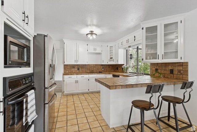 2255 E Camino Way Way S, Cottonwood Heights, UT 84121 - kitchen featuring black appliances, a peninsula, tile countertops, and tasteful backsplash