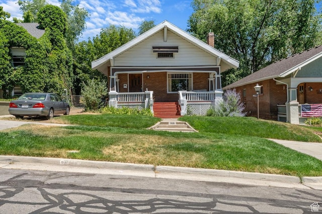 168 N T St E, Salt Lake City, UT 84103 - bungalow-style home featuring covered porch, a front lawn, brick siding, and a chimney