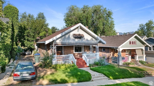 168 N T St E, Salt Lake City, UT 84103 - bungalow-style house with covered porch, brick siding, a front yard, and stairway
