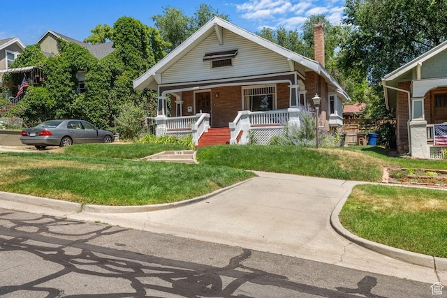 168 N T St E, Salt Lake City, UT 84103 - bungalow featuring brick siding, a chimney, covered porch, and a front yard