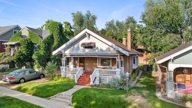 168 N T St E, Salt Lake City, UT 84103 - bungalow-style home with a porch, brick siding, a front yard, a chimney, and stairway