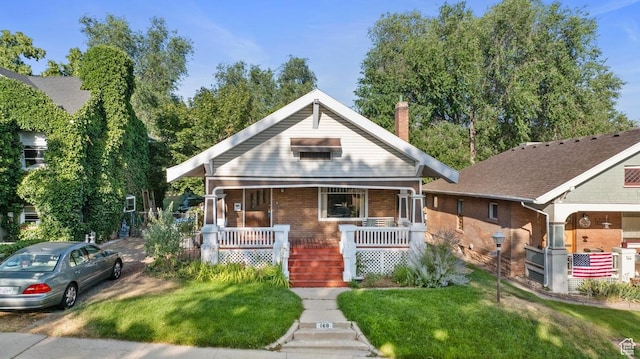 168 N T St E, Salt Lake City, UT 84103 - bungalow-style house with a porch, brick siding, a front yard, and a chimney