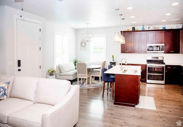 6122 W Lake Ave S, South Jordan, UT 84009 - kitchen featuring appliances with stainless steel finishes, open floor plan, light wood finished floors, recessed lighting, and a kitchen breakfast bar