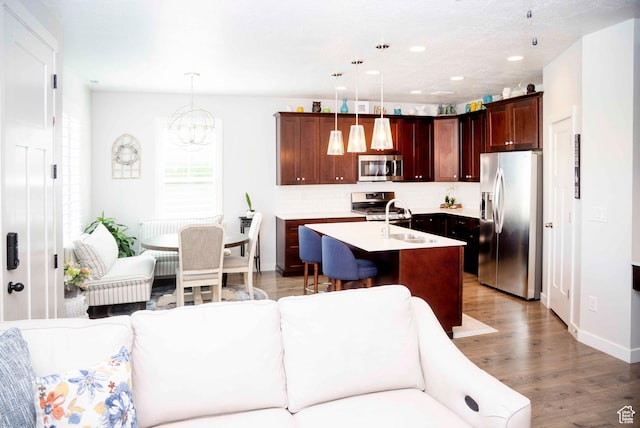 6122 W Lake Ave S, South Jordan, UT 84009 - kitchen with appliances with stainless steel finishes, tasteful backsplash, light countertops, a center island with sink, and a chandelier