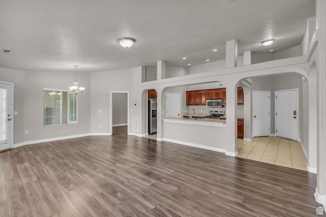 1195 W Dallin Dr Unit 304, Pleasant Grove, UT 84062 - unfurnished living room with arched walkways, a chandelier, light wood-type flooring, a textured ceiling, and recessed lighting