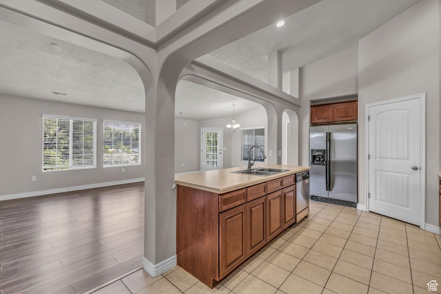 1195 W Dallin Dr Unit 304, Pleasant Grove, UT 84062 - kitchen with stainless steel appliances, arched walkways, open floor plan, a chandelier, and brown cabinetry
