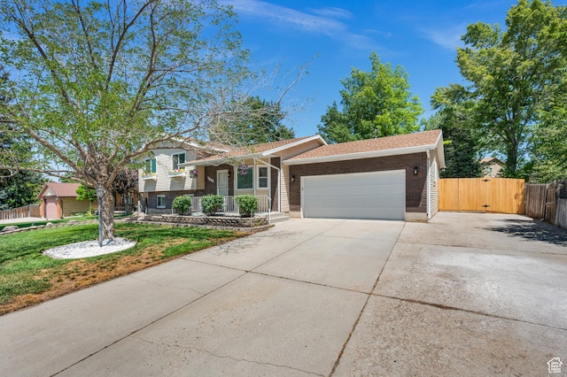 1609 E Sego Lily Dr, Sandy, UT 84092 - tri-level home with an attached garage, brick siding, concrete driveway, a gate, and a porch