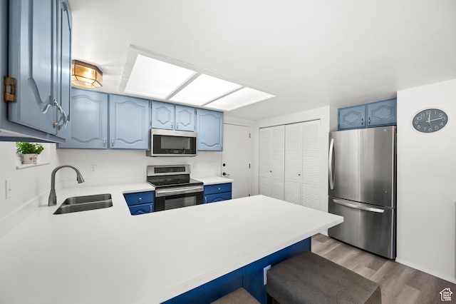 1609 E Sego Lily Dr, Sandy, UT 84092 - kitchen featuring appliances with stainless steel finishes, blue cabinetry, a peninsula, light wood-style floors, and light countertops