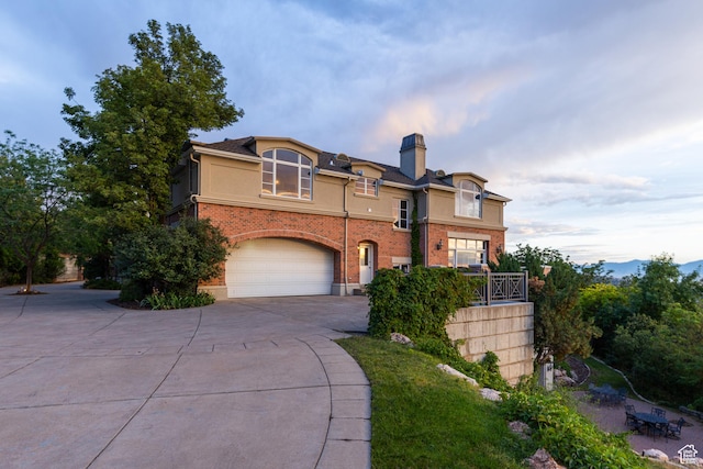 1781 Lorien Dr, Bountiful, UT 84010 - view of front facade with concrete driveway, a garage, a chimney, stucco siding, and brick siding