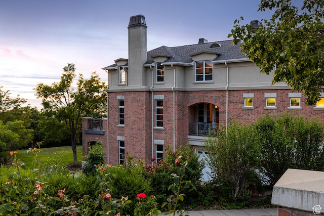 1781 Lorien Dr, Bountiful, UT 84010 - rear view of house featuring stucco siding, a chimney, a balcony, and brick siding