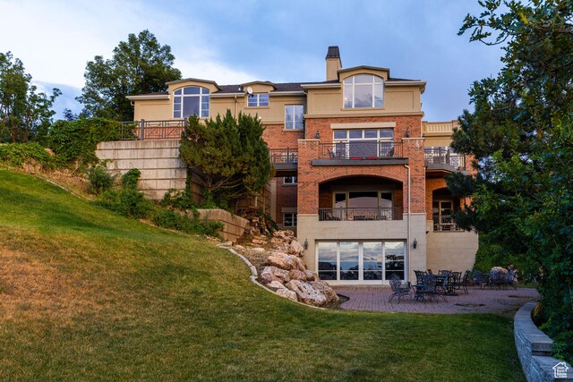1781 Lorien Dr, Bountiful, UT 84010 - back of house with a balcony, a yard, a patio area, a chimney, and stucco siding