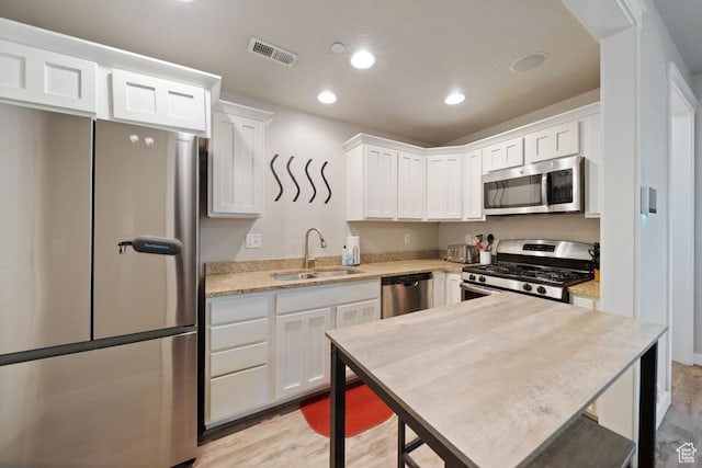 862 W Capraia Ct, Midvale, UT 84047 - kitchen featuring appliances with stainless steel finishes, white cabinets, light wood finished floors, light stone counters, and recessed lighting