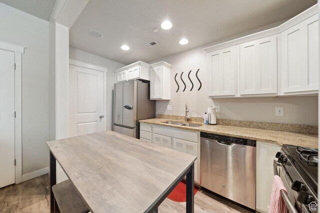 862 W Capraia Ct, Midvale, UT 84047 - kitchen with appliances with stainless steel finishes, light wood-style flooring, white cabinetry, recessed lighting, and light stone counters