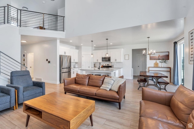 131 N Desert Sage Dr, Saratoga Springs, UT 84045 - living area with a chandelier, a towering ceiling, light wood-style flooring, stairway, and recessed lighting