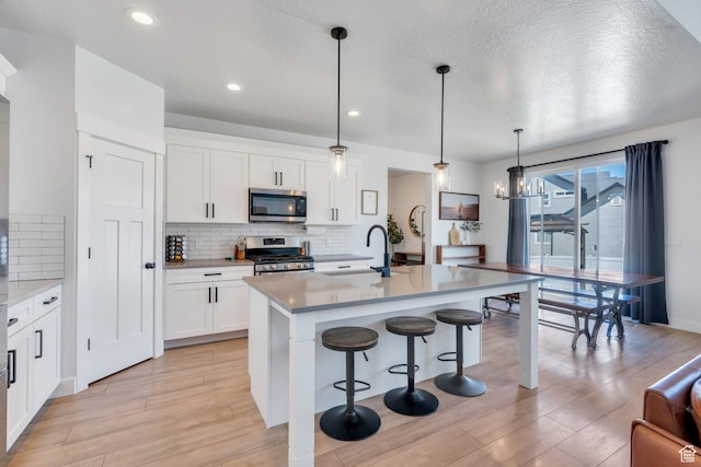 131 N Desert Sage Dr, Saratoga Springs, UT 84045 - kitchen featuring stainless steel appliances, a kitchen bar, backsplash, light wood-style flooring, and recessed lighting