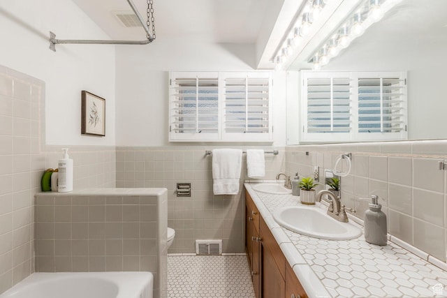 2722 E Eagle Way, Salt Lake City, UT 84108 - bathroom featuring tile walls, double vanity, a tub to relax in, tile patterned floors, and a wainscoted wall
