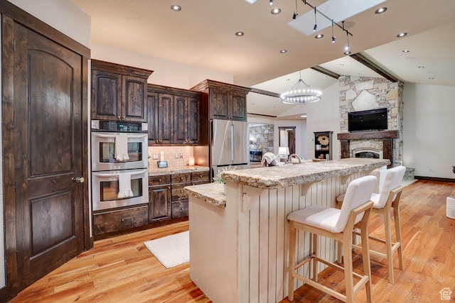 1307 N Dutch Highland Dr, Midway, UT 84049 - kitchen with stainless steel appliances, light wood-style flooring, dark brown cabinets, open floor plan, and a breakfast bar area
