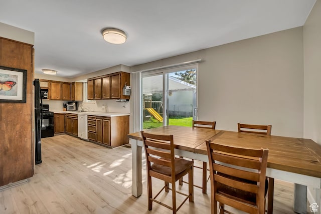 1261 E Sandra Cir, Murray, UT 84121 - kitchen with black appliances, light wood-style floors, light countertops, and brown cabinets