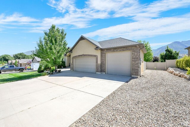 7496 S 1740 E, South Weber, UT 84405 - view of front facade featuring an attached garage, a mountain view, driveway, stucco siding, and a shingled roof