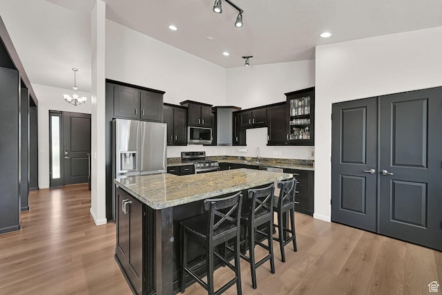 7496 S 1740 E, South Weber, UT 84405 - kitchen featuring stainless steel appliances, light stone countertops, a spacious island, light wood finished floors, and a kitchen bar