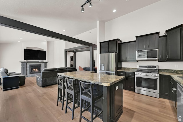 7496 S 1740 E, South Weber, UT 84405 - kitchen featuring stainless steel appliances, dark cabinetry, a kitchen island, light stone countertops, and recessed lighting