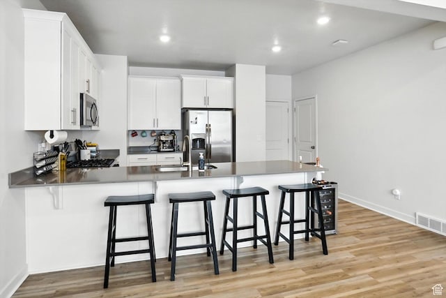 3724 W Soft Whisper Way, Herriman, UT 84096 - kitchen featuring stainless steel appliances, a peninsula, light wood-type flooring, white cabinets, and recessed lighting