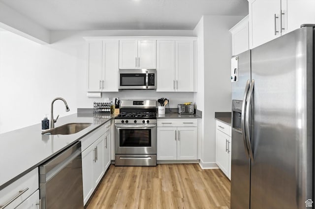 3724 W Soft Whisper Way, Herriman, UT 84096 - kitchen with stainless steel appliances, light wood finished floors, white cabinets, and dark countertops