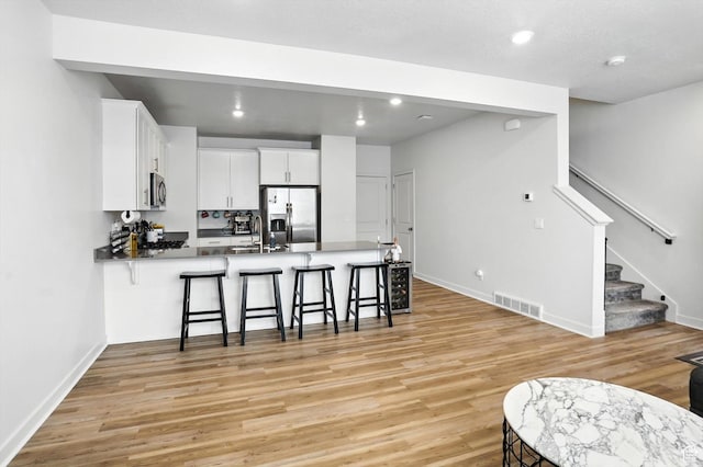 3724 W Soft Whisper Way, Herriman, UT 84096 - kitchen featuring stainless steel appliances, a peninsula, light wood-style flooring, a breakfast bar, and recessed lighting