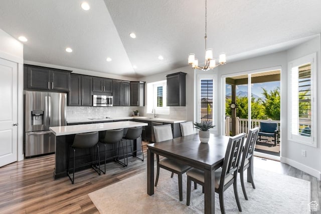11709 S 2610 W, Riverton, UT 84065 - dining area with light wood-type flooring, a chandelier, recessed lighting, vaulted ceiling, and a textured ceiling