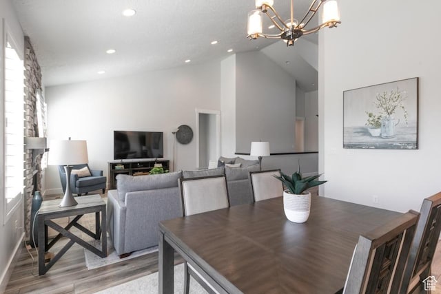 11709 S 2610 W, Riverton, UT 84065 - dining area with wood finished floors, a chandelier, recessed lighting, a stone fireplace, and high vaulted ceiling