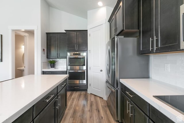 11709 S 2610 W, Riverton, UT 84065 - kitchen with appliances with stainless steel finishes, vaulted ceiling, light countertops, backsplash, and dark wood finished floors