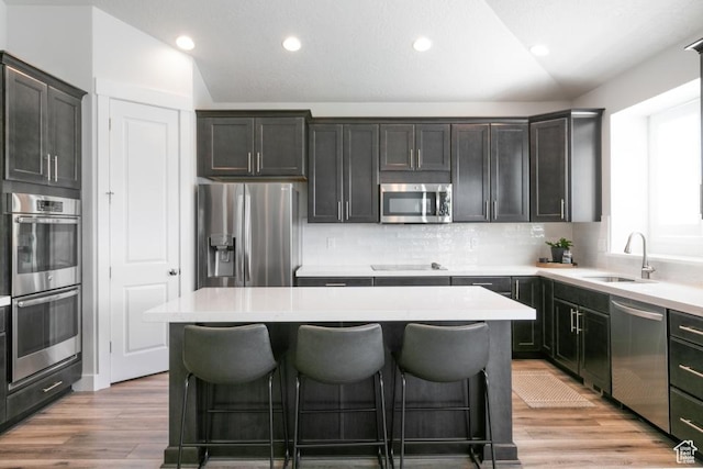11709 S 2610 W, Riverton, UT 84065 - kitchen featuring appliances with stainless steel finishes, vaulted ceiling, a center island, a kitchen breakfast bar, and decorative backsplash
