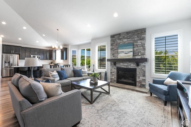 11709 S 2610 W, Riverton, UT 84065 - living room with light wood-style floors, lofted ceiling, a chandelier, a stone fireplace, and recessed lighting