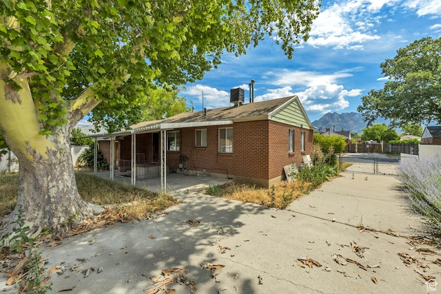 5764 S Hansen Cir E, Murray, UT 84107 - view of side of property with brick siding, a gate, a mountain view, a patio, and roof with shingles