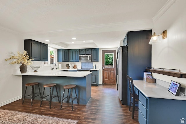 2779 E 3575 N, Layton, UT 84040 - kitchen with stainless steel appliances, a peninsula, a breakfast bar area, ornamental molding, and dark wood-style flooring