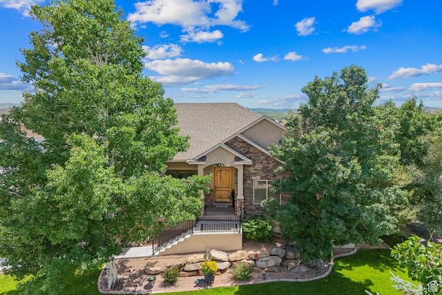 294 W Willow Ct Unit 12, Francis, UT 84036 - view of property hidden behind natural elements featuring stone siding, a front yard, a shingled roof, and stucco siding