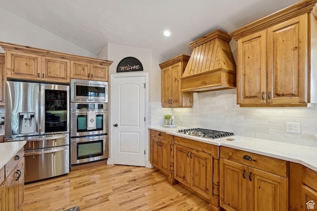 294 W Willow Ct Unit 12, Francis, UT 84036 - kitchen with stainless steel appliances, custom range hood, light countertops, backsplash, and light wood-type flooring