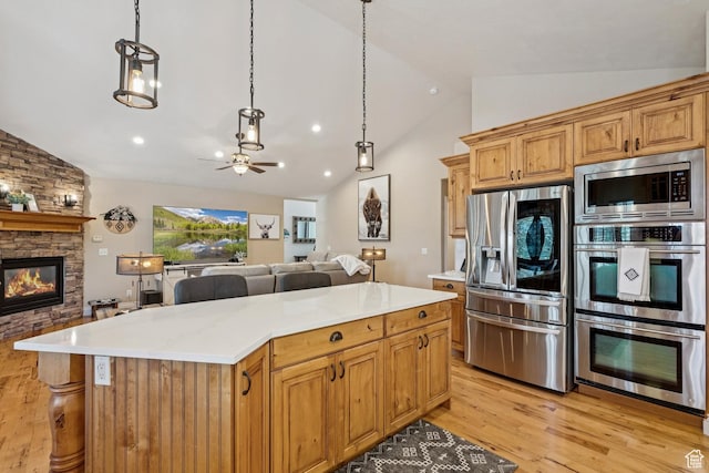 294 W Willow Ct Unit 12, Francis, UT 84036 - kitchen featuring stainless steel appliances, lofted ceiling, open floor plan, light wood-type flooring, and a fireplace
