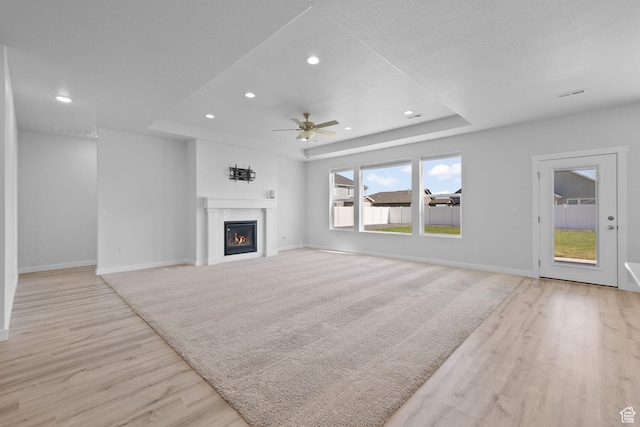 3105 W 3150 N, Plain City, UT 84404 - unfurnished living room with a tray ceiling, light wood-style floors, ceiling fan, recessed lighting, and a glass covered fireplace