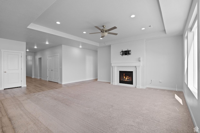 3105 W 3150 N, Plain City, UT 84404 - unfurnished living room with a raised ceiling, a ceiling fan, recessed lighting, a warm lit fireplace, and light colored carpet