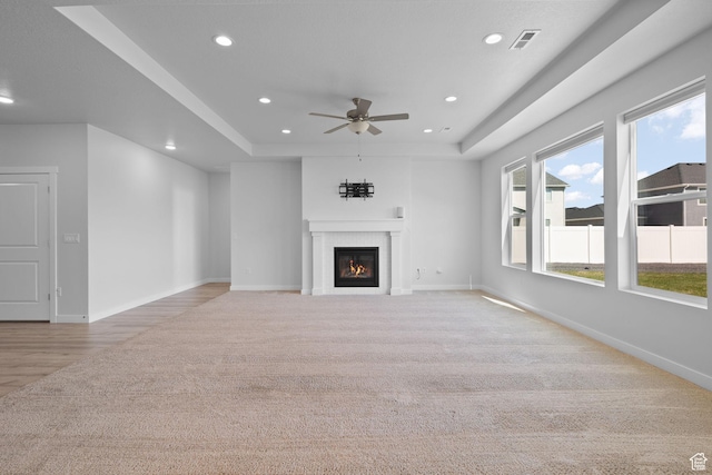 3105 W 3150 N, Plain City, UT 84404 - unfurnished living room with light carpet, a tray ceiling, recessed lighting, a ceiling fan, and a glass covered fireplace