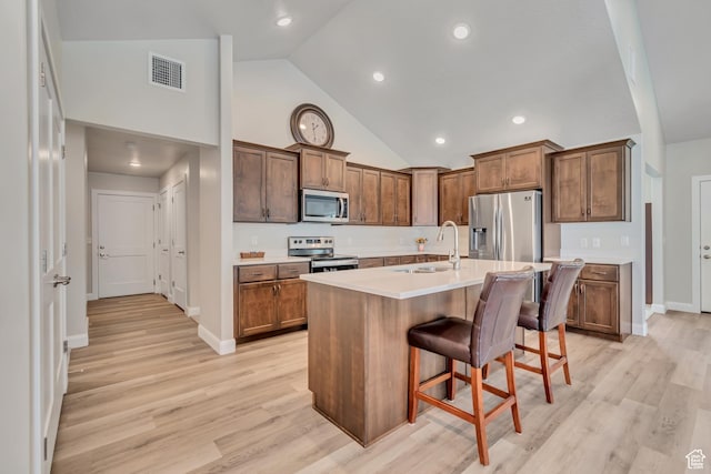 453 S Short Horse Ln Unit C, Saratoga Springs, UT 84045 - kitchen featuring appliances with stainless steel finishes, a breakfast bar, an island with sink, light countertops, and light wood finished floors