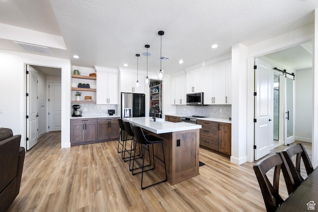 507 N 3650 W, Hurricane, UT 84737 - kitchen featuring appliances with stainless steel finishes, a breakfast bar area, light countertops, decorative backsplash, and a barn door