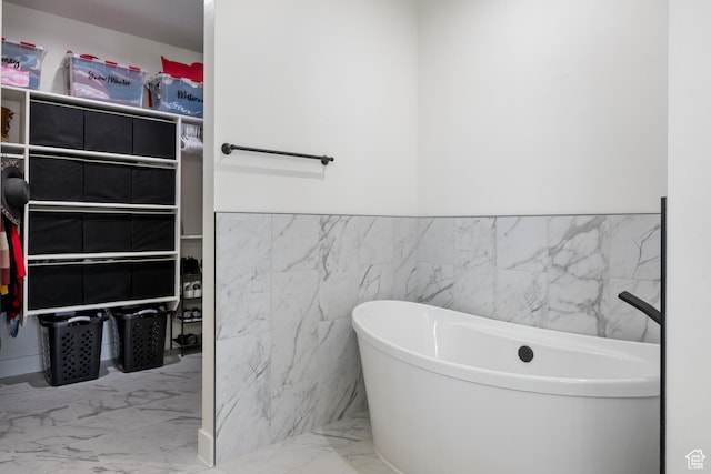507 N 3650 W, Hurricane, UT 84737 - bathroom featuring a freestanding tub, marble look tile flooring, tile walls, and a wainscoted wall