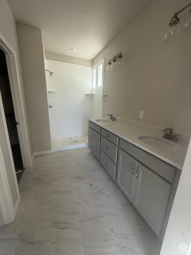 6184 W 11800 S Unit 508, Riverton, UT 84096 - bathroom with a tile shower, marble finish floors, a textured ceiling, and double vanity