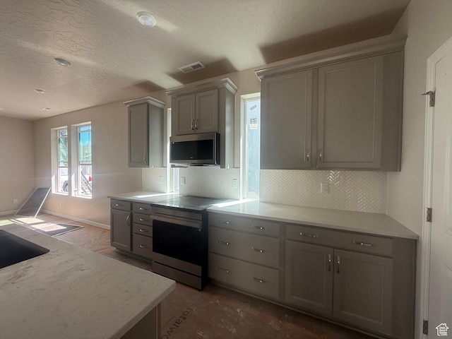 6184 W 11800 S Unit 508, Riverton, UT 84096 - kitchen with stainless steel appliances, gray cabinetry, decorative backsplash, and a textured ceiling