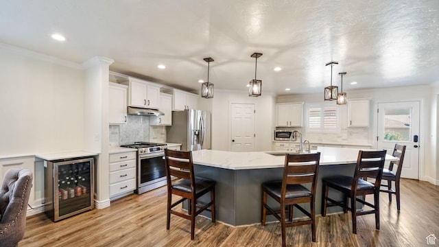 14267 S Palo Alto Dr, Herriman, UT 84096 - kitchen featuring stainless steel appliances, beverage cooler, under cabinet range hood, backsplash, and ornamental molding