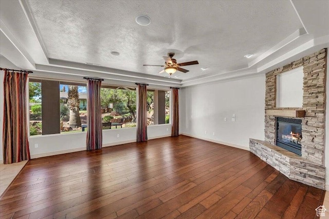 1319 W Red Butte Dr W, Washington, UT 84780 - unfurnished living room featuring a raised ceiling, a stone fireplace, ceiling fan, a textured ceiling, and dark wood-type flooring